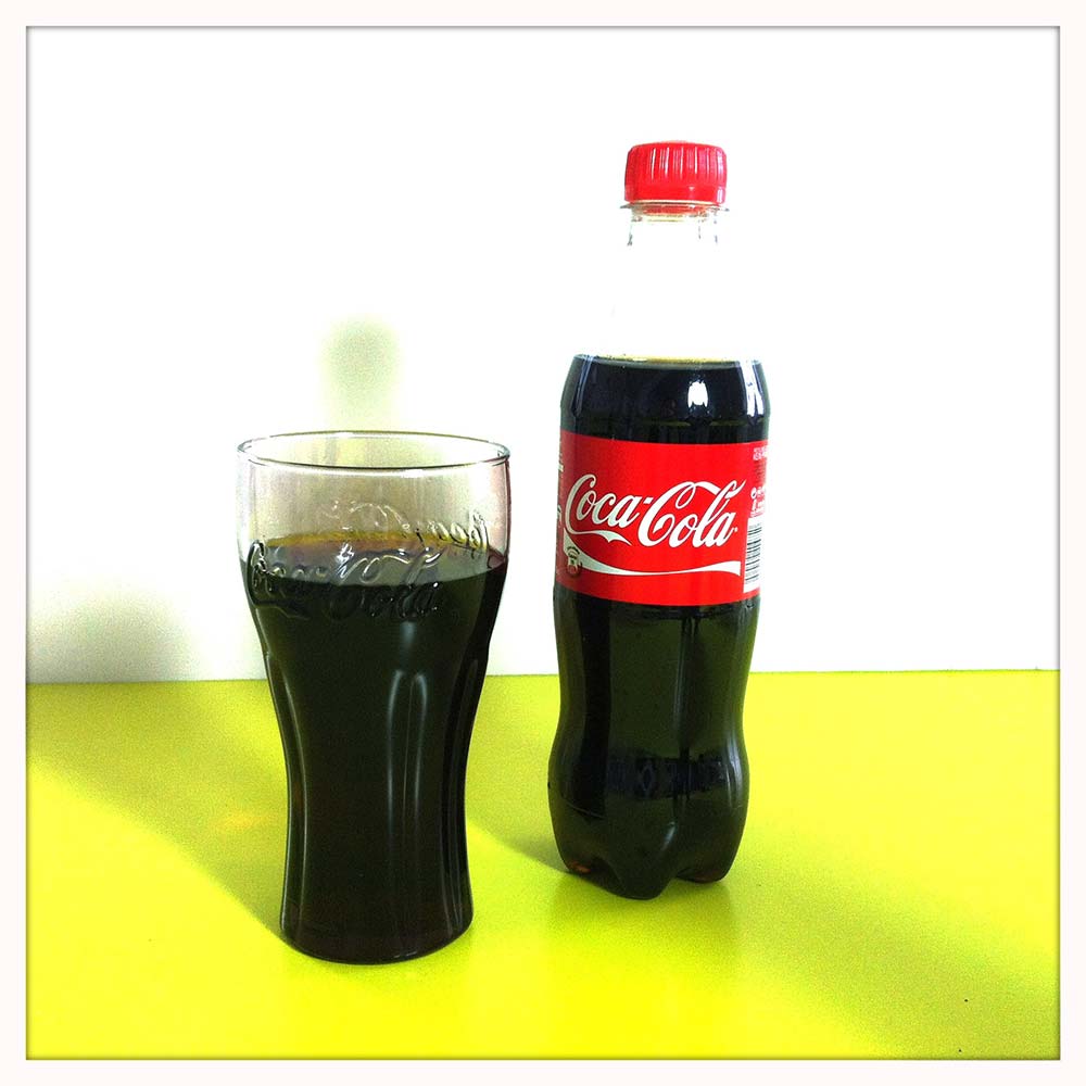 Eine Flasche Coca-Cola und ein mit Coke gefülltes Trinkglas.